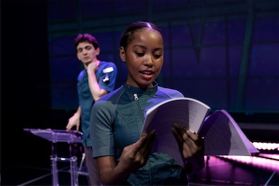 Aaron Greenberg as D-503 and Cassandra Umaña as O-90.